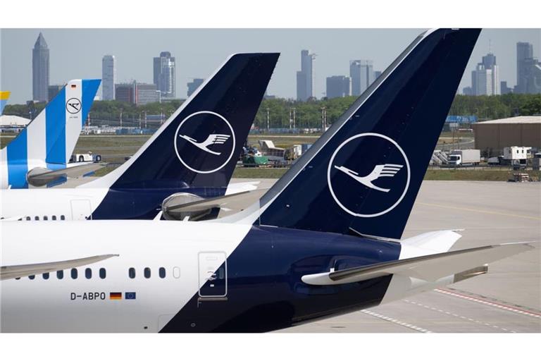 Passagiermaschinen der Lufthansa und der Condor stehen am Flughafen Frankfurt, während im Hintergrund die Bankentürme von Frankfurt zu sehen sind. (Symbolbild)