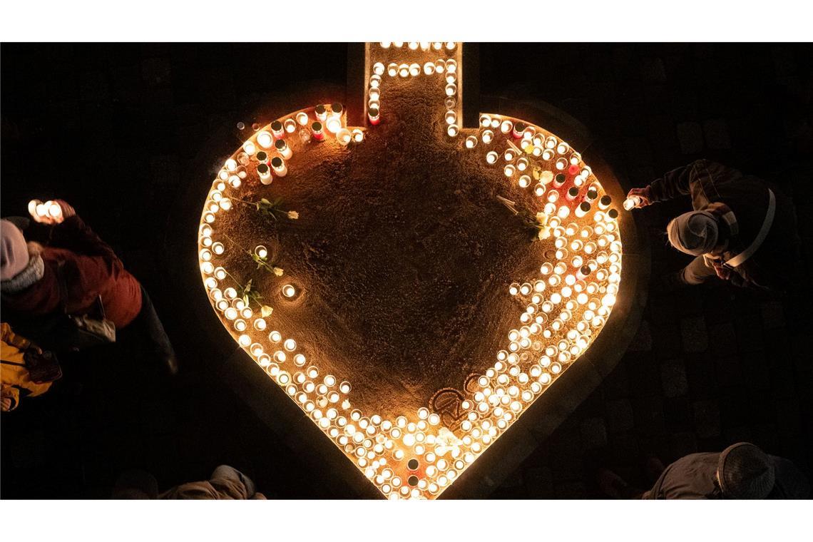 Passanten entzünden auf dem Neumarkt Kerzen am 81. Jahrestag der Zerstörung Dresdens.