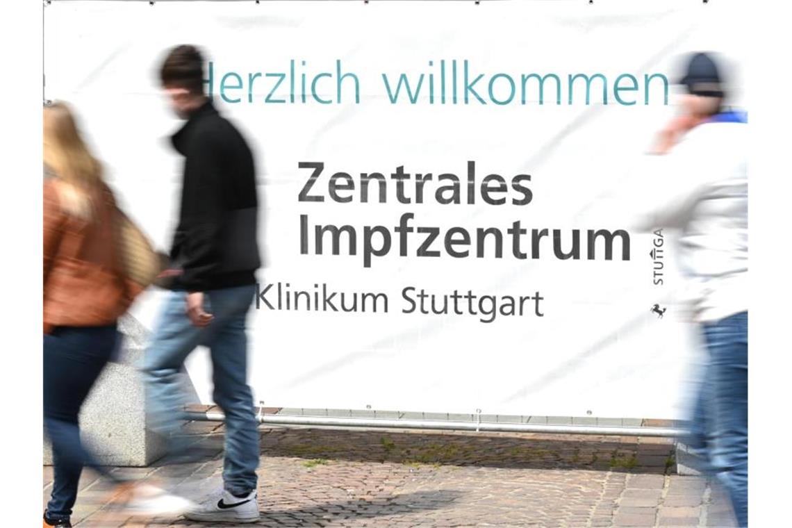 Impfzentren im Südwesten stellen zeitweise ihren Betrieb ein Passanten gehen am Eingangsschild des Impfzentrum des Klinikums Stuttgart vorbei. Foto: Bernd Weißbrod/dpa/Archivbild