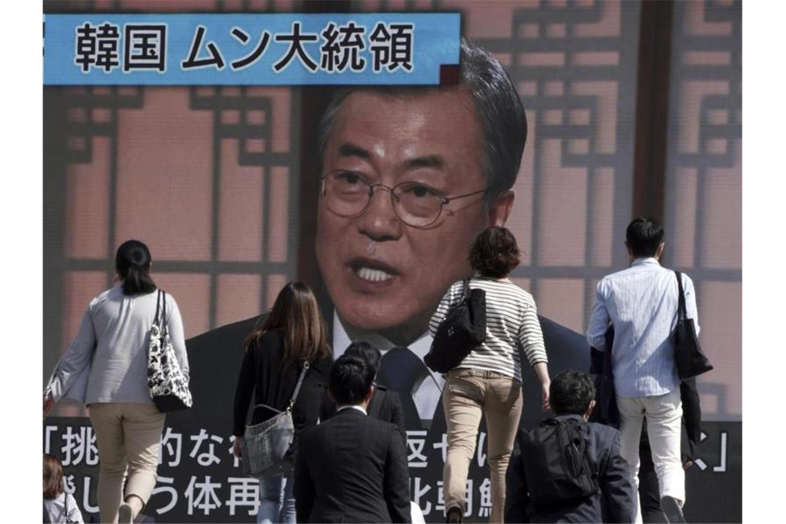 Passanten gehen an einem Bildschirm vorbei, auf dem eine Nachrichtensendung mit dem südkoreanischen Präsidenten Moon Jae-in zu sehen ist. Der südkoreanische Präsident Moon forderte Nordkorea auf, von Handlungen Abstand zu nehmen, die die Diplomatie behindern könnten. Foto: Eugene Hoshiko/AP