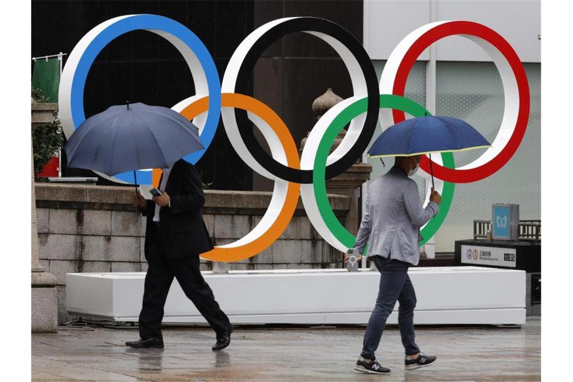 Bach-Ankunft mit Tiefschlag: Fan-Ausschluss in Tokio Passanten gehen an Olympischen Ringen in Tokio vorbei. Während der Spiele wird es keine Fans in den Stadien geben. Foto: Rodrigo Reyes Marin/ZUMA Wire/dpa