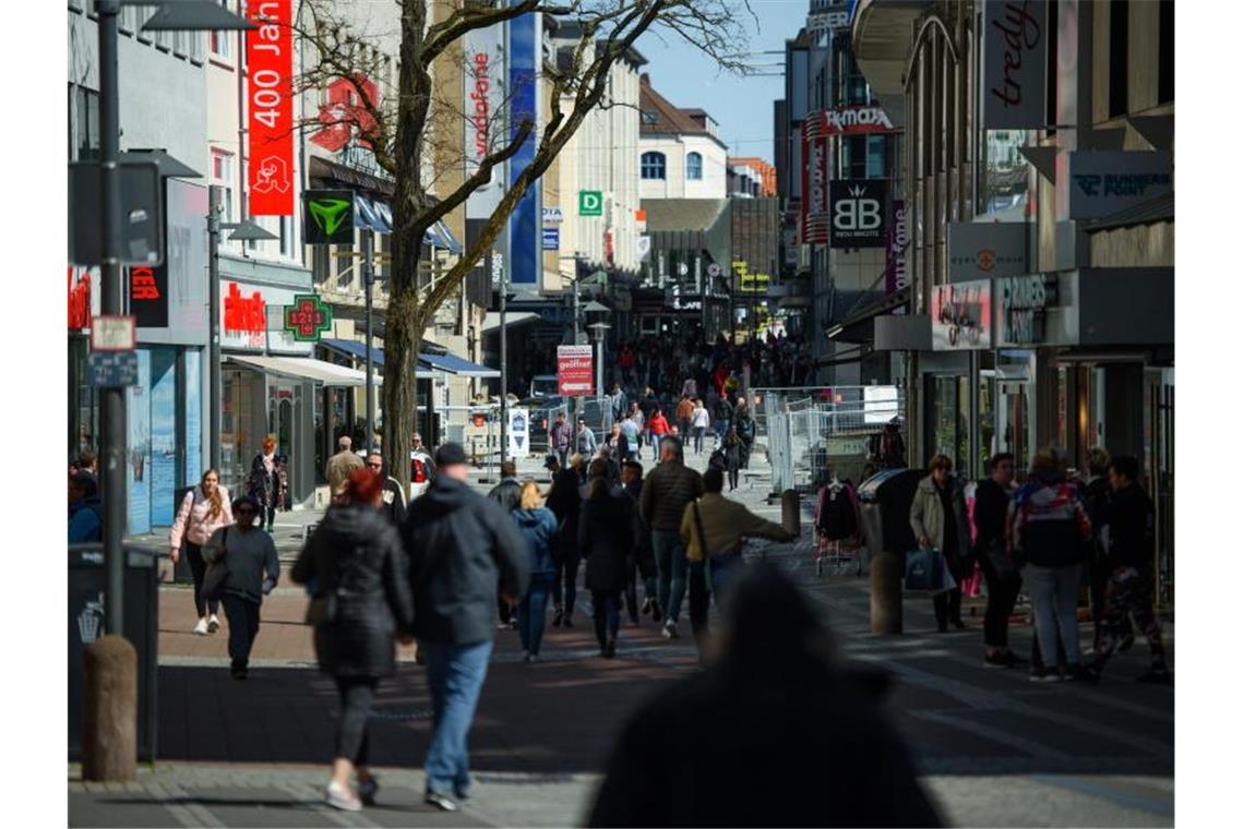 Passanten gehen bei Sonnenschein durch eine Einkaufsstraße in einer Fußgängerzone. Foto: Gregor Fischer/dpa/Symbolbild