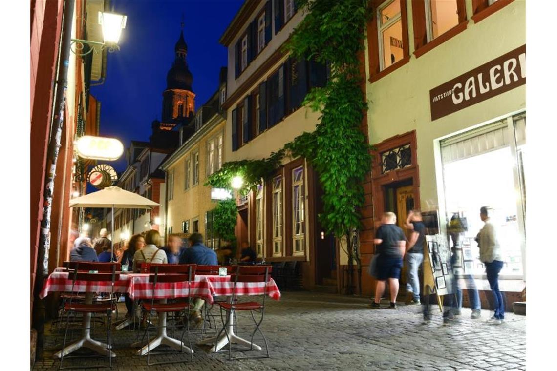 Passanten gehen durch die Altstadt in Heidelberg. Foto: Uwe Anspach/dpa/Archivbild