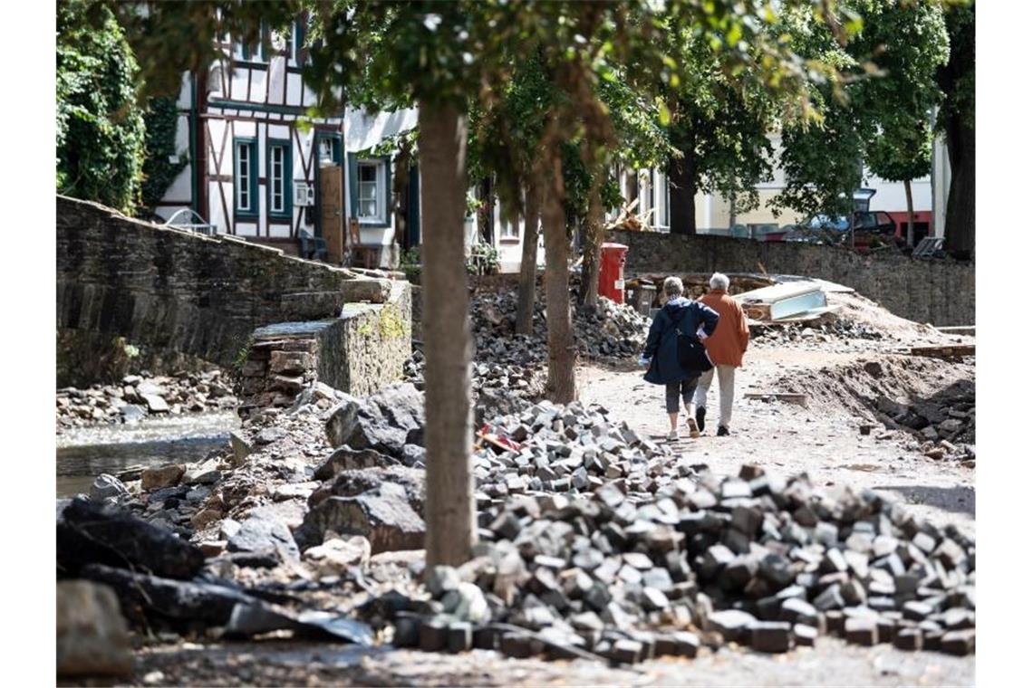 Passanten gehen durch die von der Flut zerstörte Innenstadt von Bad Münstereifel. Foto: Federico Gambarini/dpa