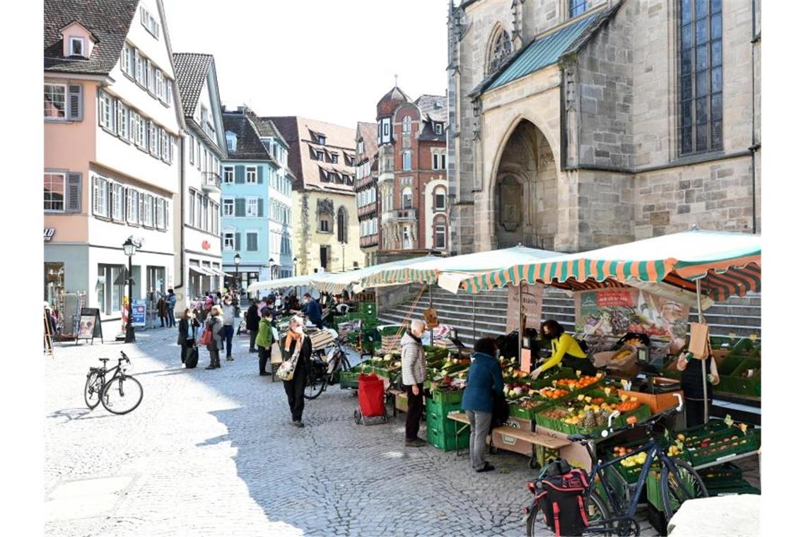 Passanten gehen in der Fußgängerzone an Marktständen vorbei. Foto: Bernd Weißbrod/dpa