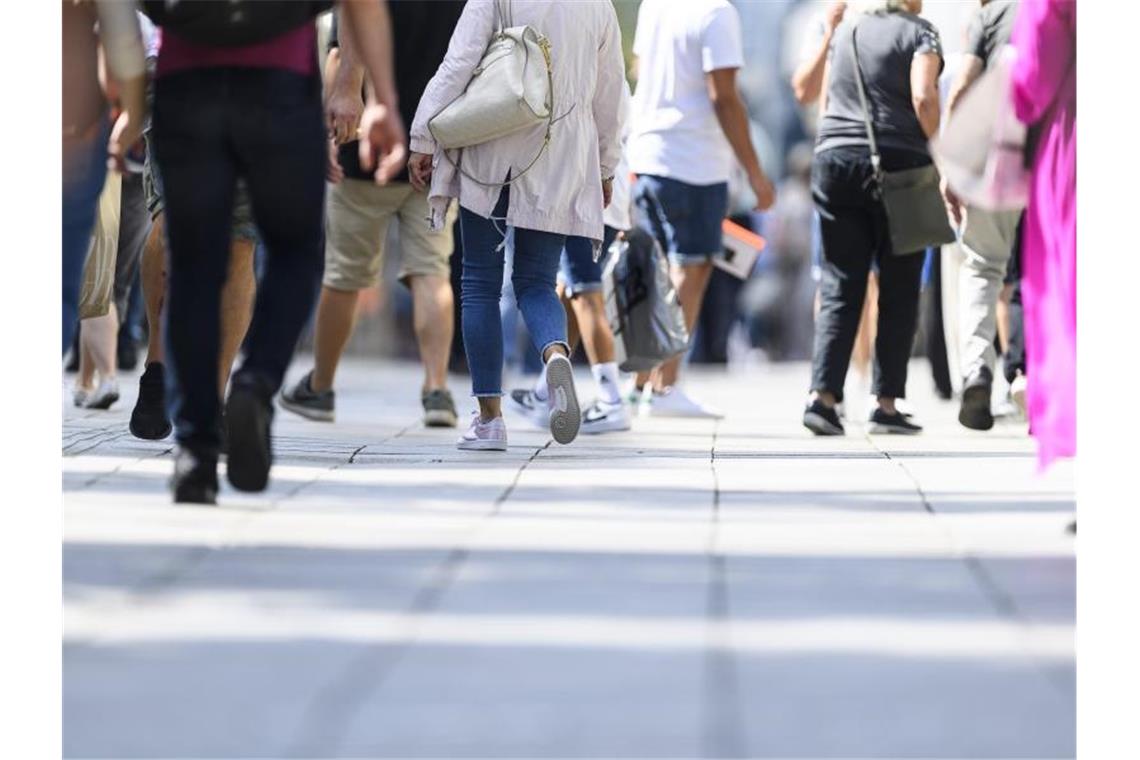 Passanten gehen über auf einer Straße. Foto: Edith Geuppert