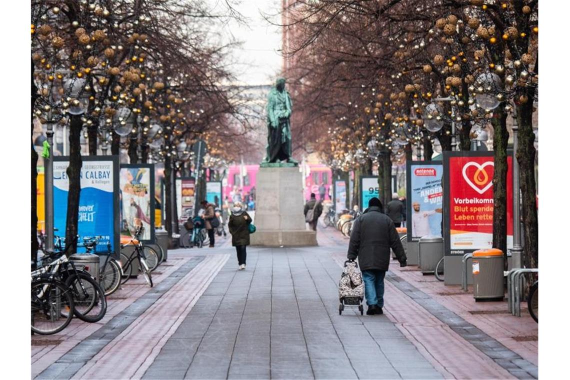 Passanten laufen durch die beinahe menschenleere Innenstadt von Hannover. Foto: Julian Stratenschulte/dpa