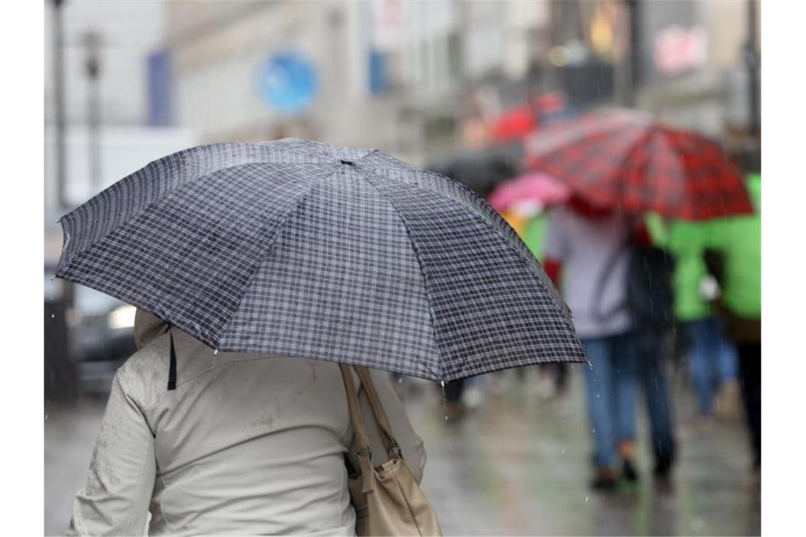 Ungemütliches Weihnachtswetter im Südwesten Passanten mit ihren Regenschirmen bei einem kräftigen Regenschauer. Foto: Roland Weihrauch/Archivbild