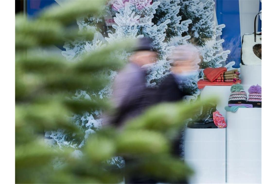 Passanten mit Mund-Nasen-Bedeckungen gehen vor einem winterlich geschmückten Schaufenster in Berlin vorbei. Foto: Christoph Soeder/dpa