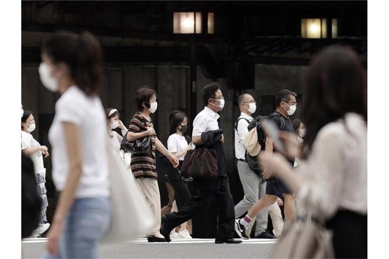 Passanten mit Mund-Nasen-Schutz in Tokio. Foto: Eugene Hoshiko/AP/dpa