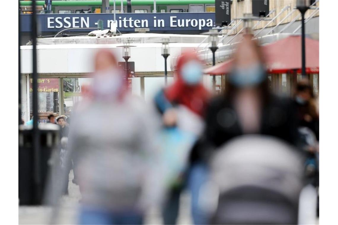 Immer mehr Corona-Hotspots - Söder für einheitliches Bußgeld Passanten mit und ohne Mund-Nasen-Schutz gehen durch eine Einkaufsstraße in Essen. Foto: Roland Weihrauch/dpa