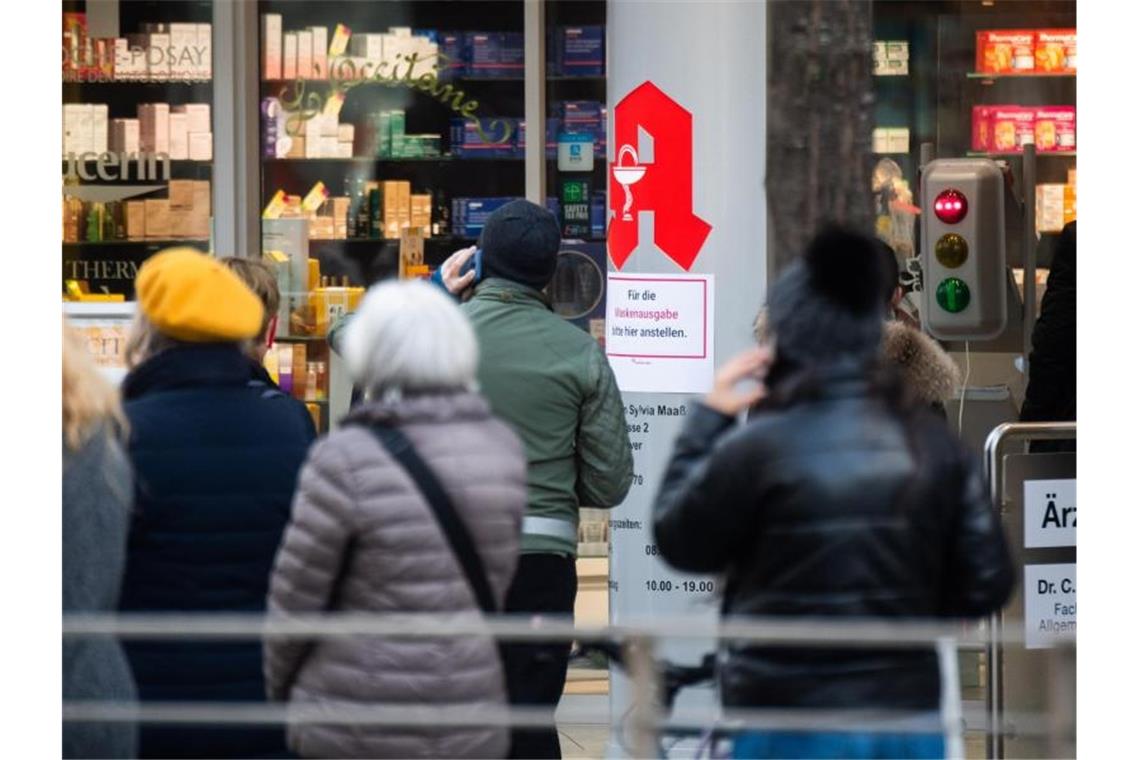 Passanten stehen Schlange vor einer Apotheke. Foto: Julian Stratenschulte/dpa