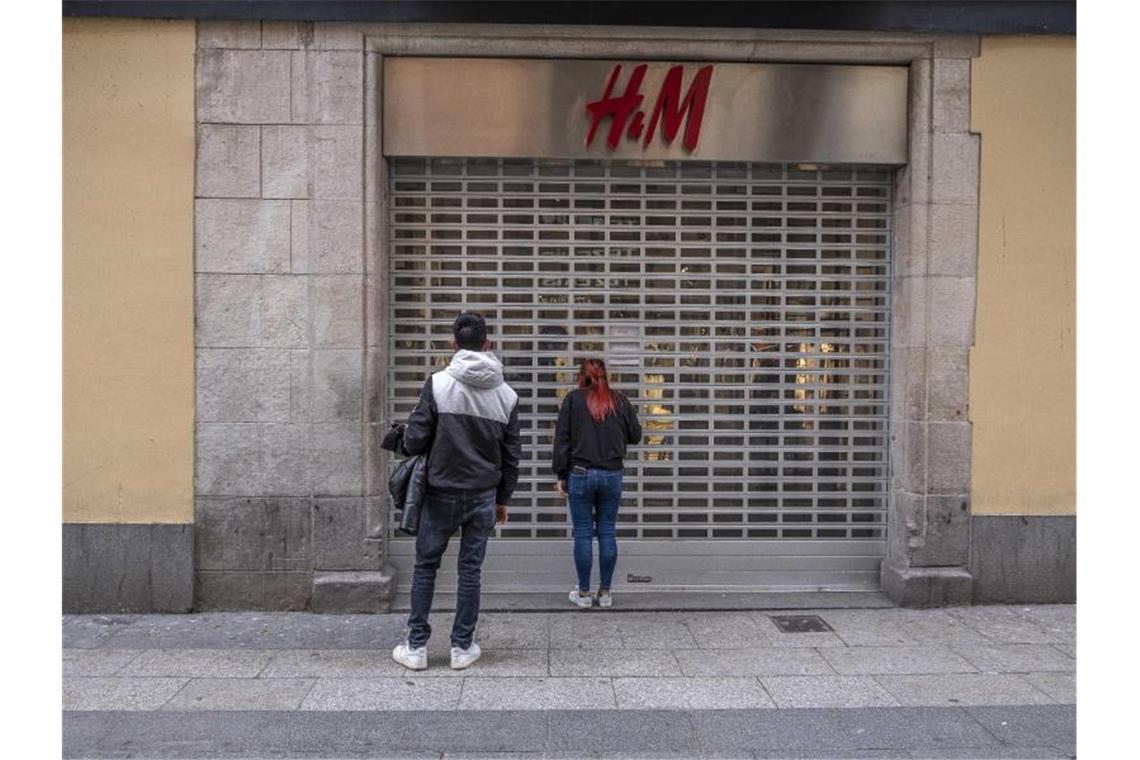 Passanten stehen vor einer geschlossenen H&M-Filiale. Foto: Paco Freire/SOPA Images via ZUMA Wire/dpa
