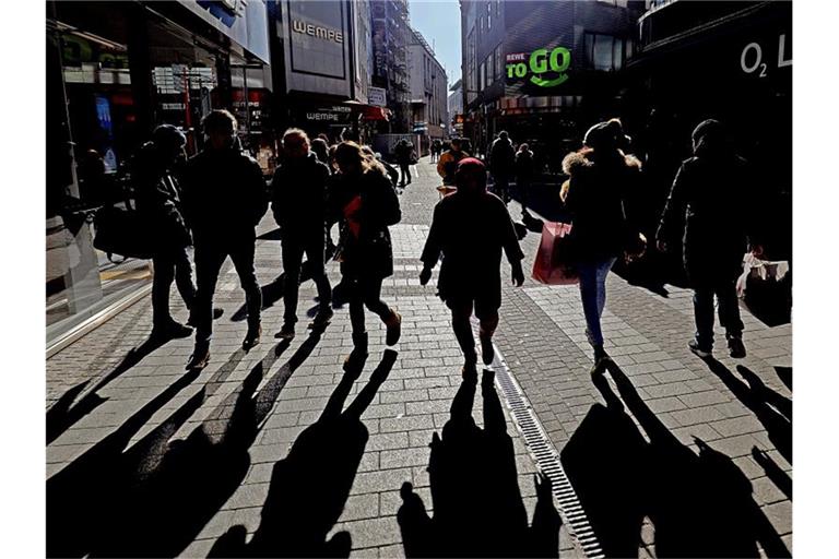 Passanten werfen in einer Kölner Fußgängerzone lange Schatten. Foto: Oliver Berg/dpa