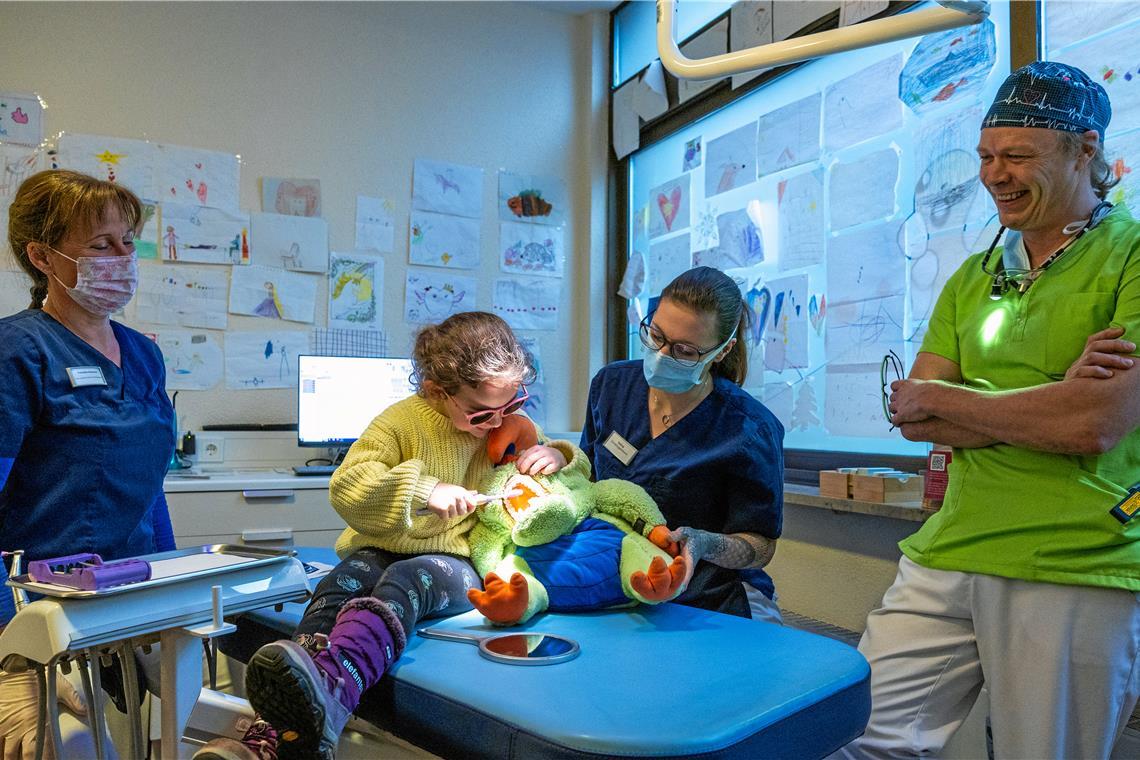 Patientin Liva übt beim Plüschtierdrachen Kai das Zähneputzen. Franziska Schumann (links) und Selina Teixeira Vilaca sowie Are Hilliges unterstützen sie dabei. Foto: Alexander Becher
