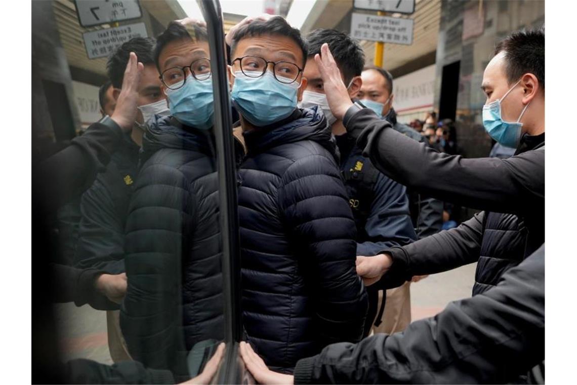 Patrick Lam (l), Herausgeber der Online-Publikation „Stand News“, wird von Polizeibeamten in einen Lieferwagen eskortiert. Foto: Vincent Yu/AP/dpa