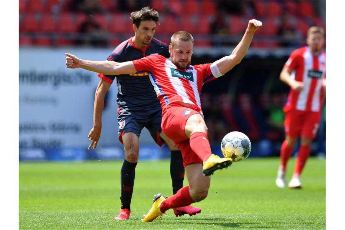 Patrick Mainka (l) vom 1. FC Heidenheim behauptet den Ball gegen den Regensburger Sebastian Stolze. Foto: Sebastian Widmann/getty/pool/dpa