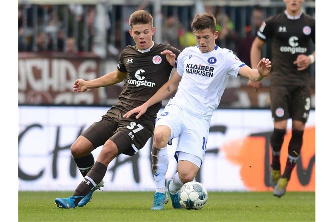 Paulis Finn Ole Becker (l) und KSC-Profi Marvin Wanitzek teilten sich mit ihren Clubs die Punkte. Foto: Daniel Bockwoldt/dpa