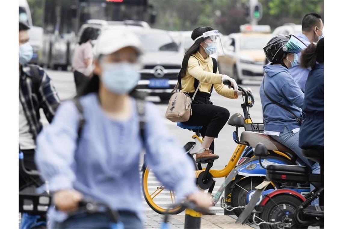 Pendler fahren in Wuhan auf Motorrädern und Fahrrädern zur Arbeit. Gut ein Jahr nach dem Ausbruch gilt das Coronavirus in China als so gut wie besiegt. Foto: kyodo/dpa