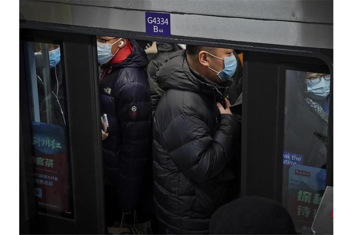 Pendler in Peking drängen sich während der Hauptverkehrszeit in eine U-Bahn. Foto: Andy Wong/AP/dpa