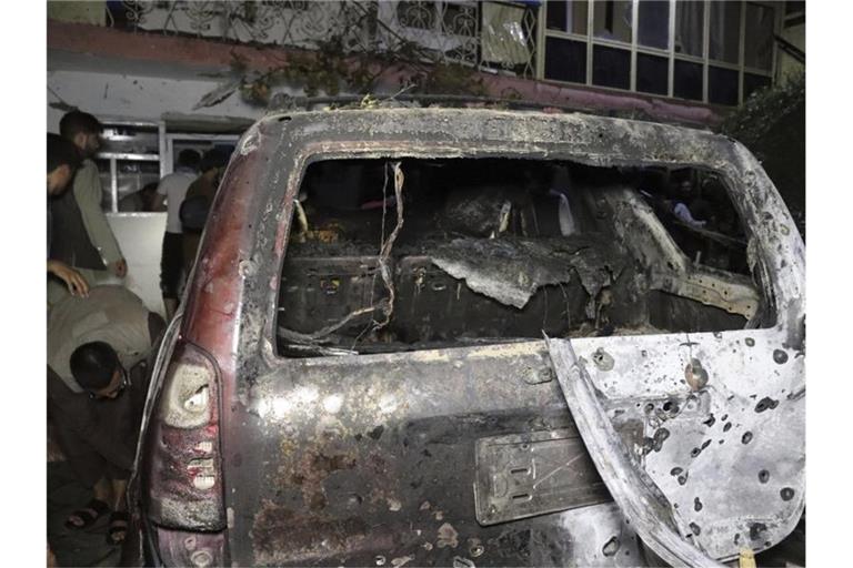 Personen betrachten ein ausgebranntes Fahrzeug in Kabul, das bei einem amerikanischen Drohnenangriff ins Visier genommen wurde. Foto: Khwaja Tawfiq Sediqi/AP/dpa