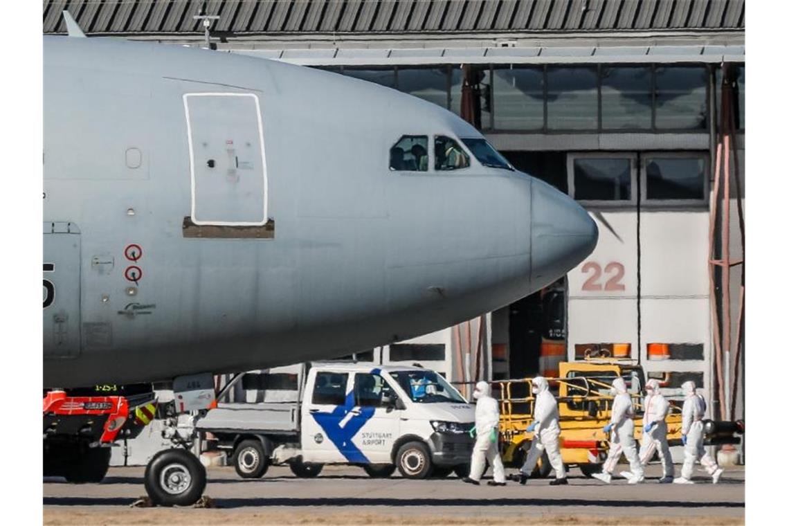 Personen in Schutzanzügen laufen in Stuttgart zu einem Airbus der Luftwaffe, um dort Rückkehrer aus der chinesischen Millionenmetropole Wuhan in Empfang zu nehmen. Foto: Christoph Schmidt/dpa