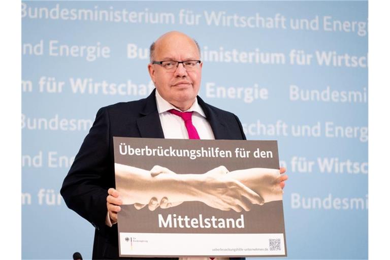 Peter Altmaier (CDU) hält ein Plakat mit der Aufschrift "Überbrückungshilfen für den Mittelstand" in den Händen. Foto: Kay Nietfeld/dpa/Archivbild