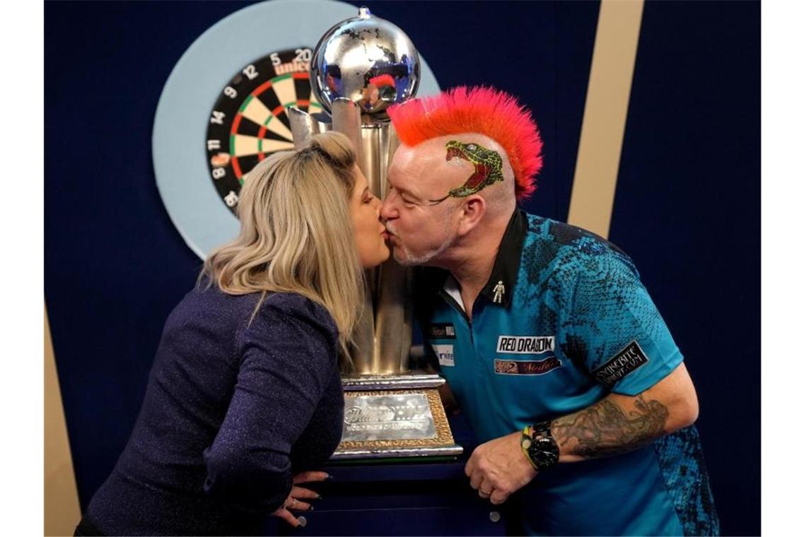 Peter Wright feiert mit seiner Frau Joanne und der Sid Waddell Trophy seinen Sieg. Foto: John Walton/PA Wire/dpa