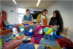 Petra Brinckmann (von links), Sabine Schopf und Christina Demertzi bewundern die zahlreichen Schals, Mützen und Socken, welche die Erlacher Höhe nun als Spende bekommen hat. Foto: Alexander Becher