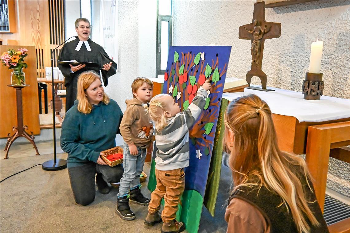Pfarrerin Ute Bögel (links) macht den Glauben bei den Kleinkindgottesdiensten an wechselnden Orten in Backnang greifbar. Beim Auftaktgottesdienst in der Petruskirche in Sachsenweiler durften die Kinder Blätter und Äpfel an einen Baum hängen. Foto: Tobias Sellmaier