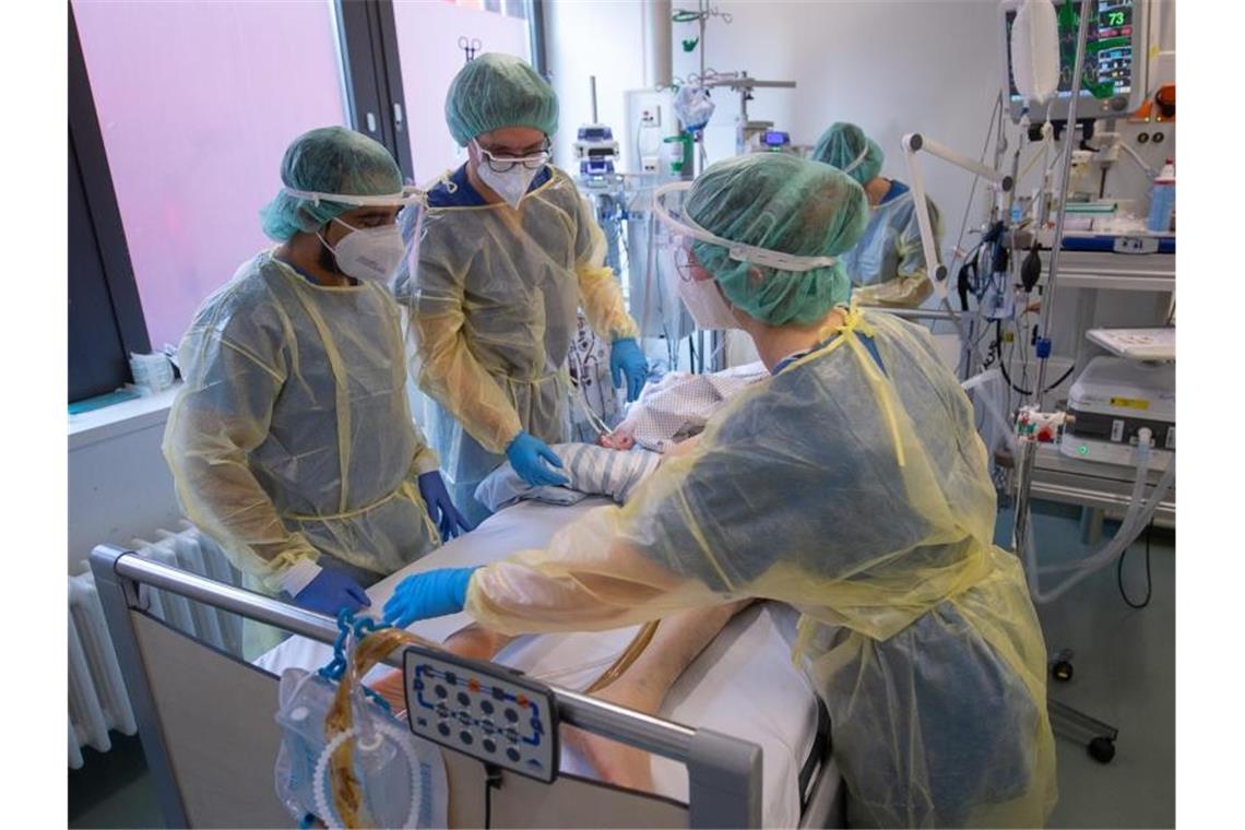 Regierung erwartet Hunderttausende Neuinfektionen pro Tag Pflegerinnen und Pfleger sowie eine Ärztin kümmern sich auf der Intensivstation für Corona-Patienten um einen Patienten. (Archivbild). Foto: Sebastian Gollnow/dpa