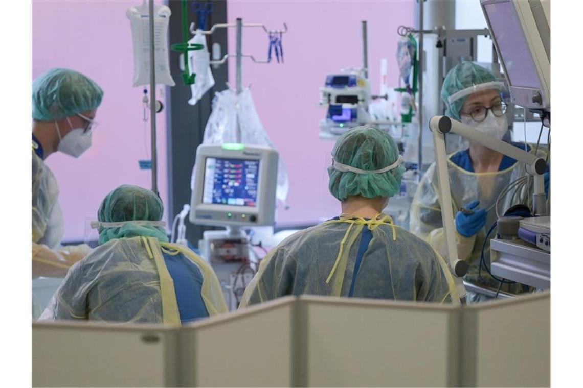 Corona verschärft Personalmangel in Kliniken Pflegerinnen und Pfleger sowie eine Ärztin kümmern sich auf der Intensivstation um einen Patienten. Foto: Sebastian Gollnow/dpa