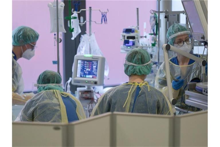 Pflegerinnen und Pfleger sowie eine Ärztin kümmern sich auf der Intensivstation um einen Patienten. Foto: Sebastian Gollnow/dpa