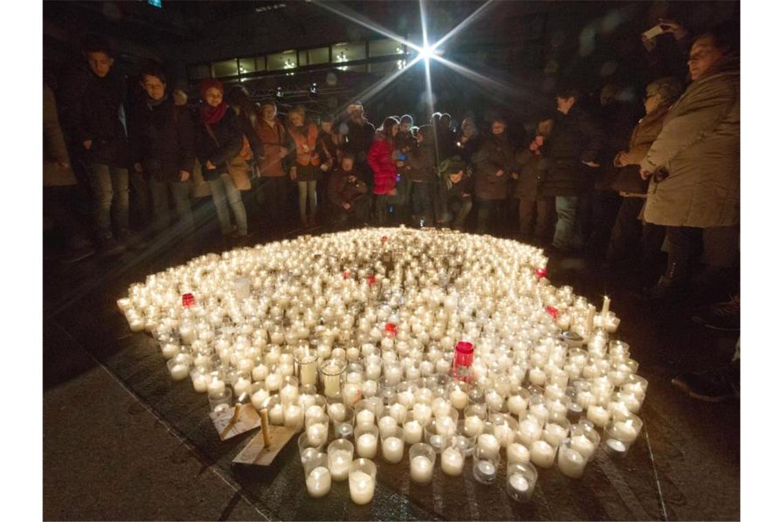 Gedenken in Pforzheim am 75. Jahrestag der Bombardierung Pforzheimer auf dem Markplatz neben brennenden Kerzen zum Gedenken an die Zerstörung der Stadt. Foto: picture alliance/dpa/Archivbild