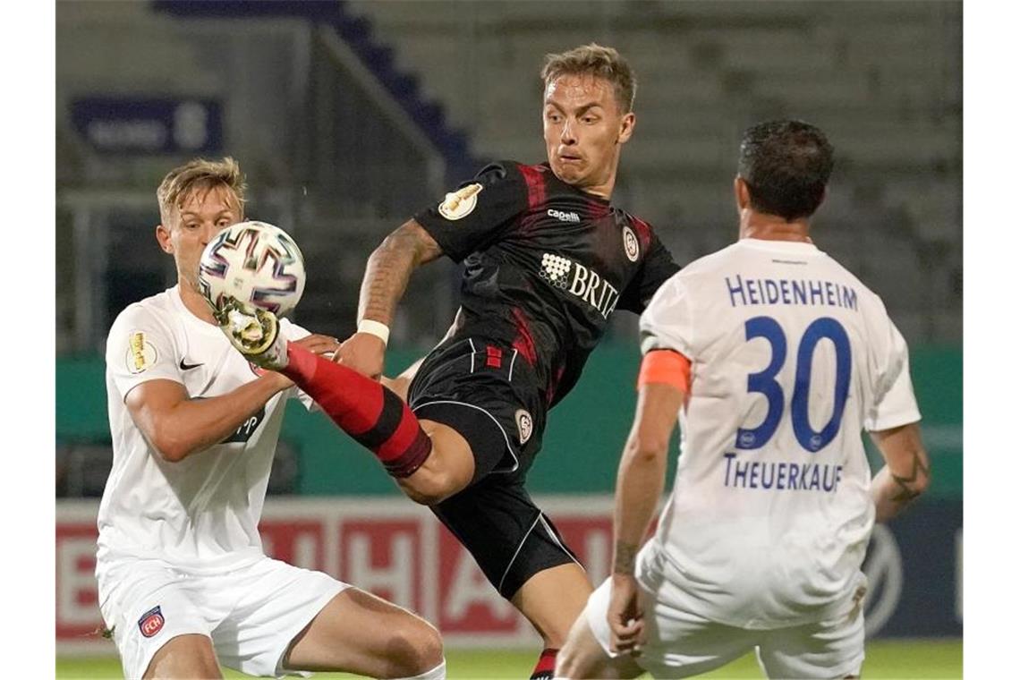 Wehen Wiesbaden bejubelt Pokal-Coup gegen Heidenheim Phillip Tietz (M) im Kampf mit Oliver Streurer (L) und Norman Theuerkauf (R) aus Heidenheim. Foto: Hasan Bratic/dpa