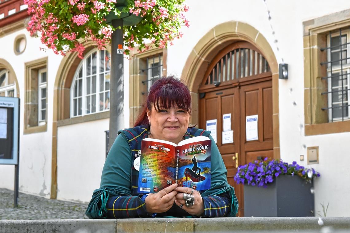 Pia Guttenson steht mit ihrem Liebesroman am Brunnen vor dem Rathaus in der Backnanger Innenstadt. Foto: T. Sellmaier