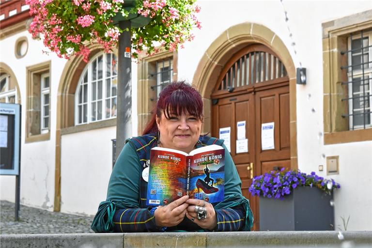 Pia Guttenson steht mit ihrem Liebesroman am Brunnen vor dem Rathaus in der Backnanger Innenstadt. Foto: T. Sellmaier