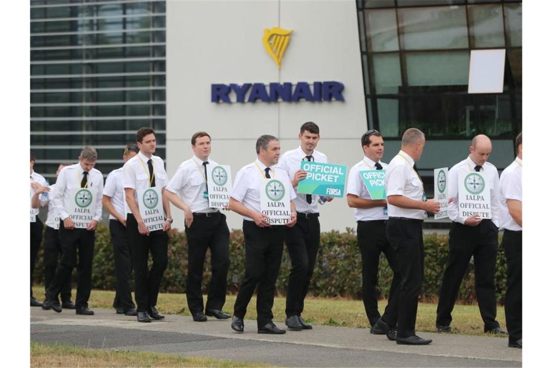 Piloten der Fluggesellschaft Ryanair streiken und stehen mit Schildern vor dem Firmensitz des Unternehmens. Die in Irland stationierten Piloten der Billigfluggesellschaft Ryanair drohen mit Streik. Foto: Niall Carson/PA Wire/dpa