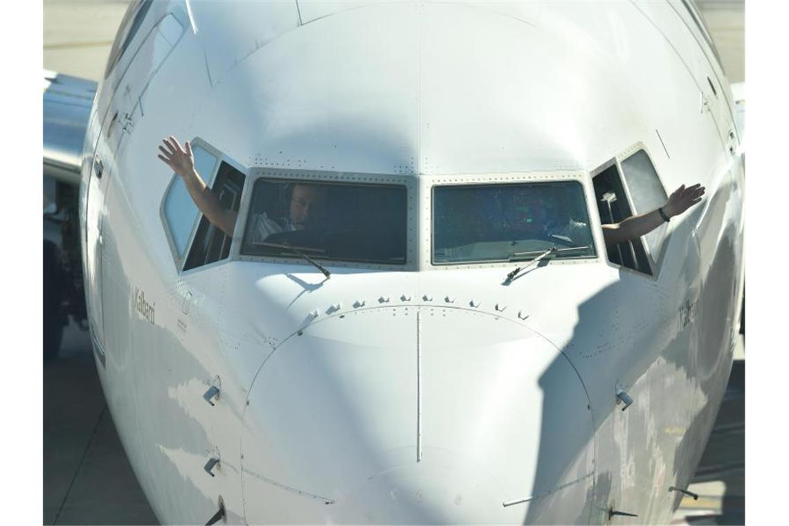 Australische Airline Qantas plant Belohnungen für Geimpfte Piloten winken aus dem Cockpit einer Passagiermaschine der Fluggesellschaft Quantas. Foto: Dean Lewins/AAP/dpa