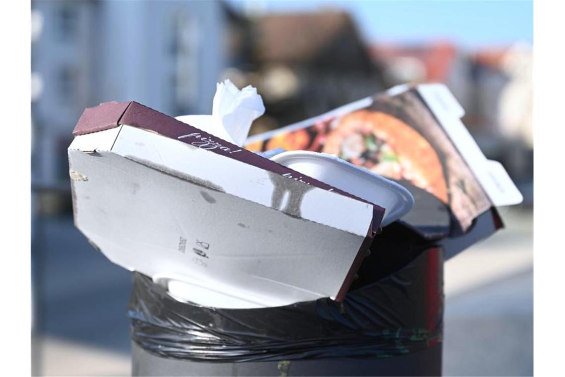 Pizzakartons und andere Essensverpackungen stecken in einem öffentlichen Mülleimer. Foto: Marijan Murat/dpa/Symbolbild