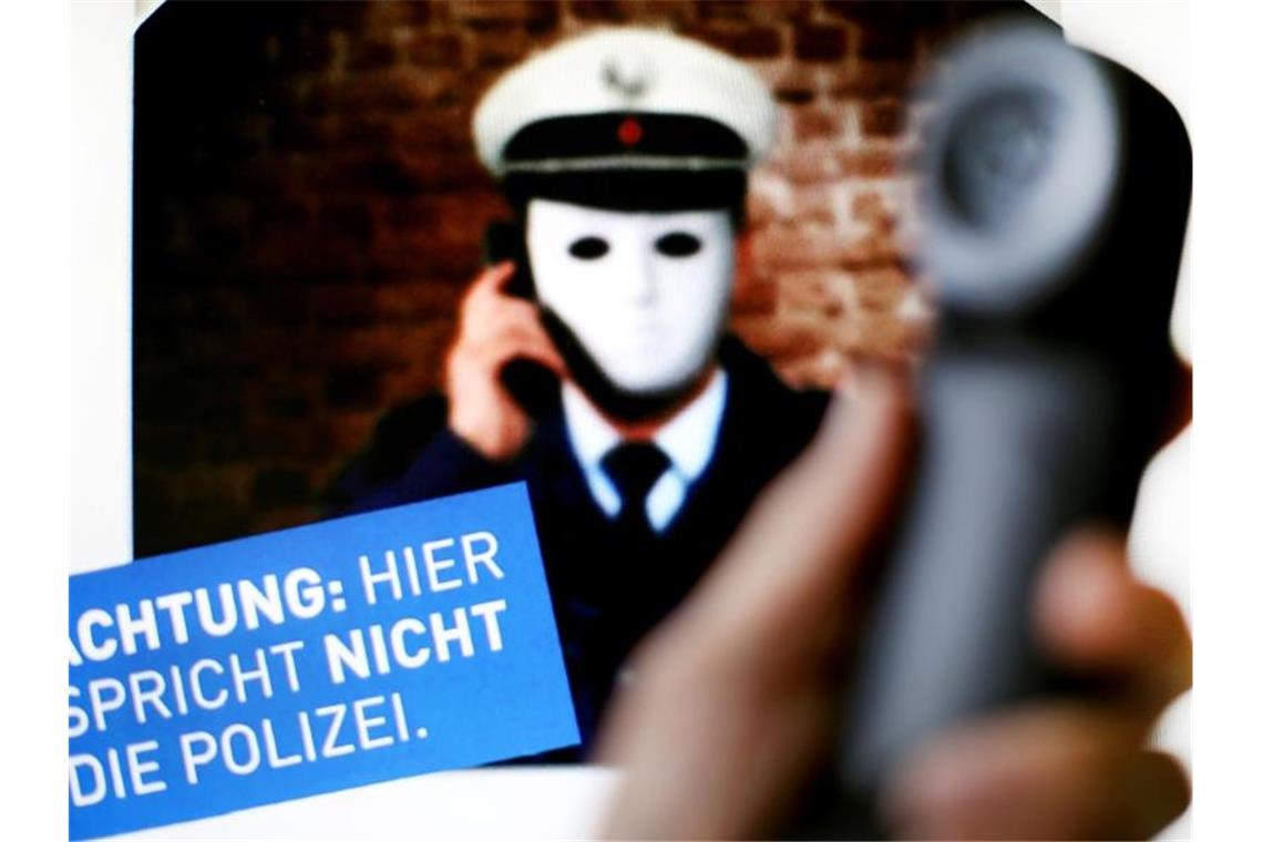 Urteil: Falscher Polizist soll Deutschland verlassen Plakat mit der Aufschrift „Achtung: Hier spricht NICHT die Polizei“ gehalten. Foto: Martin Gerten/dpa/Symbolbild