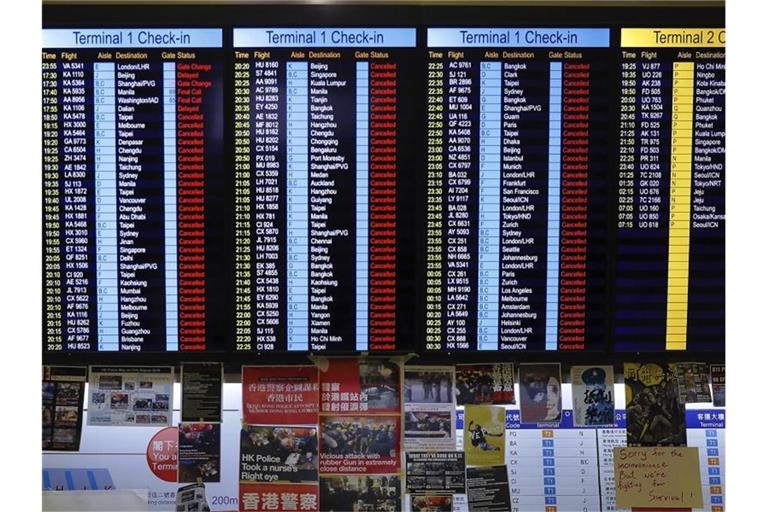 Plakate von Demonstranten unter der Fluginformationstafel des Airports. Foto: Kin Cheung/AP