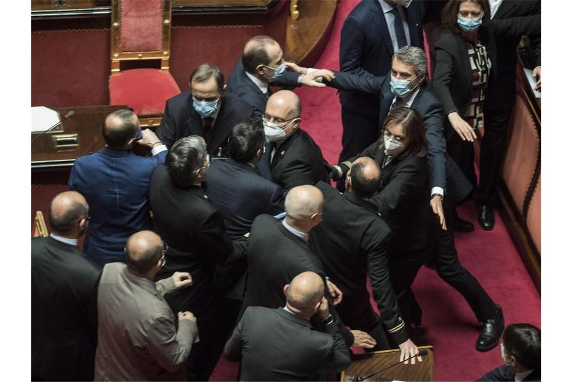 Italien entschärft Migrationsgesetze - Gerangel im Senat Platzanweiser (M) verhindern, dass Senatsmitglieder der Lega Nord (l) mit Mitgliedern der Demokratischen Partei im Senat aneinandergeraten. Foto: Roberto Monaldo/LaPresse/AP/dpa