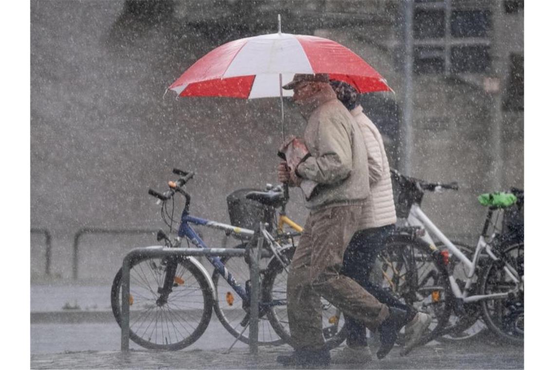 Schon 1,5 Grad mehr: Wie der Klimawandel Deutschland trifft Plötzlicher Starkregen überrascht Passanten auf den Straßen. Deutschland muss sich auf mehr extreme Wettersituationen wie Starkregen einstellen. Foto: Peter Steffen/dpa