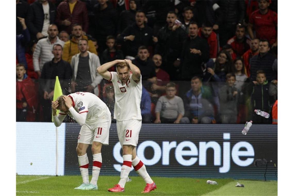 Polen Spieler schützen sich vor den Flaschenwürfen der albanischen Anhänger. Foto: Franc Zhurda/AP/dpa