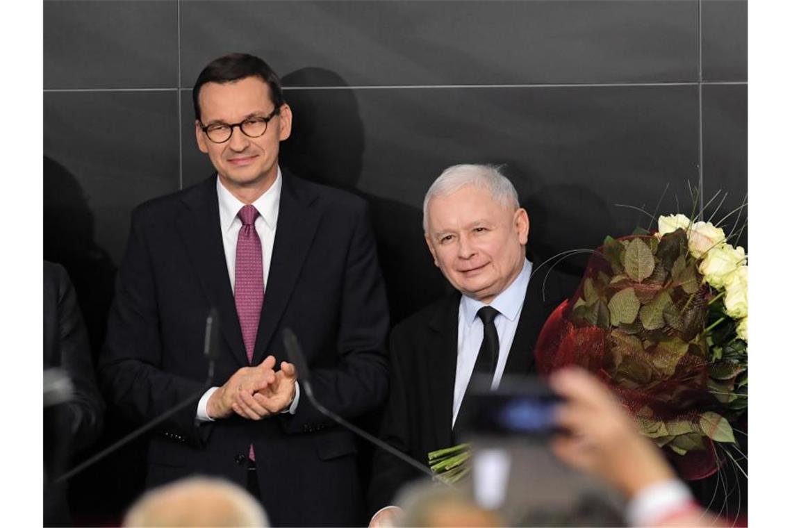 Polens Regierungschef Mateusz Morawiecki (l) und Jaroslaw Kaczynski (r), Vorsitzender der PiS-Partei, am Wahlabend in Warschau. Foto: Radek Pietruszka/PAP/dpa