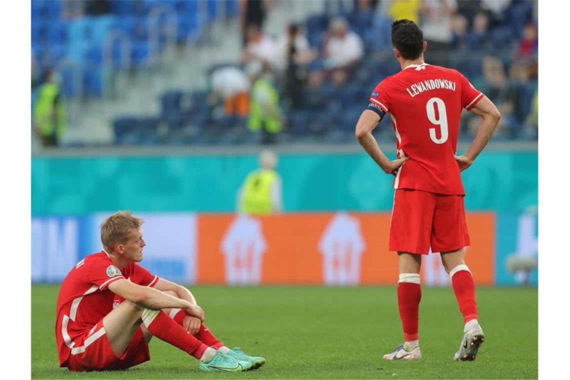 Polens Robert Lewandowski (r) steht nach Abpfiff enttäuscht auf dem Rasen. Foto: Igor Russak/dpa