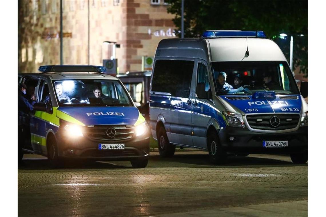 Polizei-Einsatzwagen stehen auf dem Schlossplatz, um die Einhaltung der Corona-Regeln zu kontrollieren. Foto: Christoph Schmidt/dpa