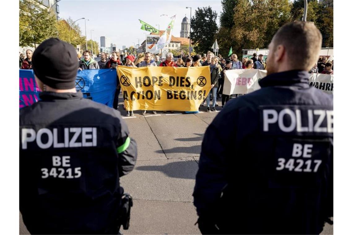Polizeibeamte beobachten in Berlin eine Blockade der Bewegung „Extinction Rebellion“. Foto: Christoph Soeder/dpa