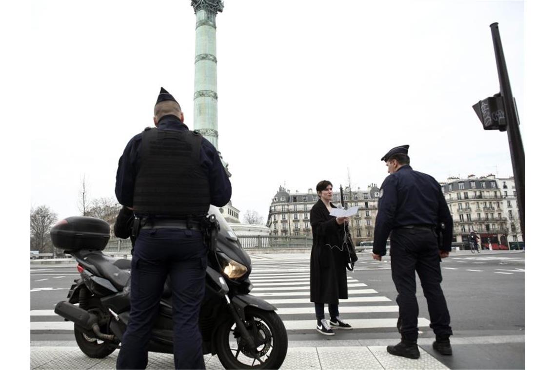 Polizeibeamte kontrollieren die Ausgangsformulare an einer Kontrollstelle in Paris. Foto: Thibault Camus/AP/dpa